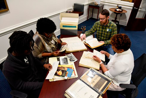 Figure 8. From bottom left, clockwise: Former Russell Library employee David Dawha, library employees Tanya Darden and Evan Leavitt, and Interim Library Director Dr. Shaundra Walker peruse local historical materials. Photo credit: Anna Leavitt. Reprinted with permission.